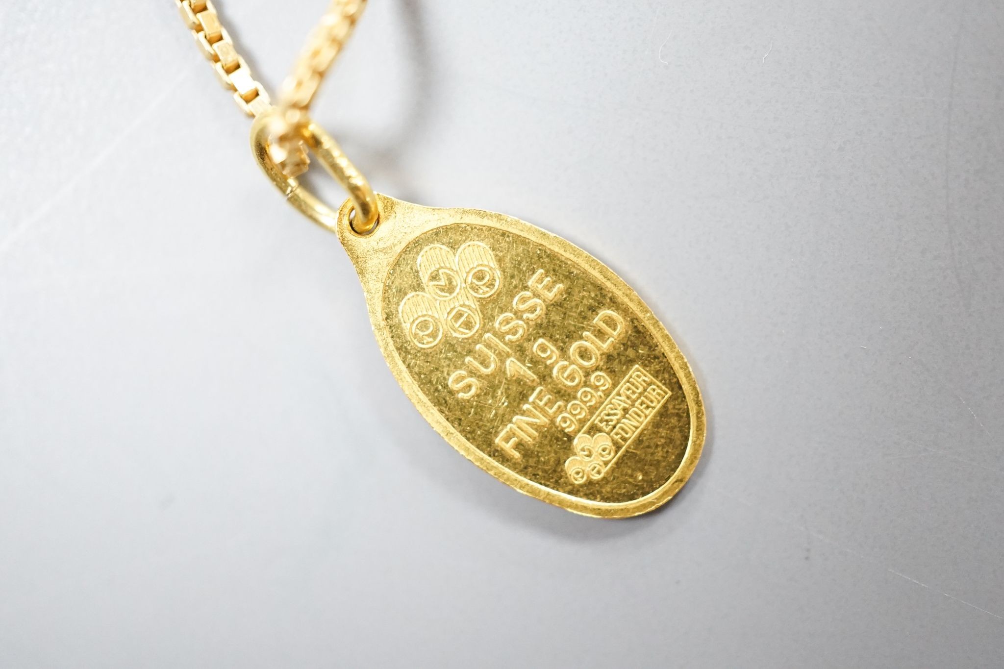 A Suisse '1g Fine Gold' yellow metal pendant, 15mm, on a 750 chain, gross 6.3 grams.